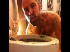 Naughty guy cleaning a toilet bowl full of shit using his tongue